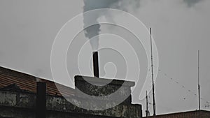 Steam and smoke getting out from smokestack at weathered building roof of power plant on a winter sky