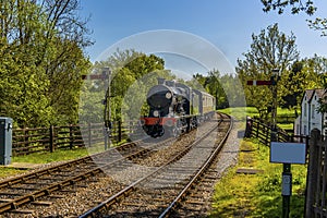 A steam train going through signals on a railway line in Sussex, UK