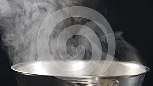 Steam or Vapour clouds rising from boiling steel frying pan on stove. Steam from pan while cooking. Cooking process in