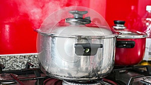 Steam or Vapour clouds rising from boiling water in saucepan on stove. Steam from pan while cooking.