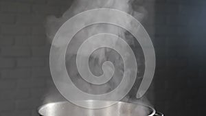 Steam or Vapour clouds rising from boiling water in saucepan on stove. Steam from pan while cooking. Cooking process in