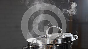 Steam or Vapour clouds rising from boiling water in saucepan on stove. Steam from pan while cooking. Cooking process in