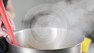 Steam or Vapour clouds rising from boiling water in saucepan on stove. Steam from pan while cooking. Cooking process in