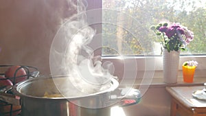 Steam or Vapour clouds rising from boiling water in saucepan on stove. Steam from pan while cooking potato. Cooking