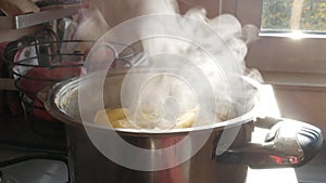 Steam or Vapour clouds rising from boiling water in saucepan on stove. Steam from pan while cooking potato. Cooking