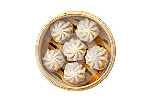 Steamed baozi dumplings stuffed with meat in a bamboo steamer. Isolated, white background. Top view.