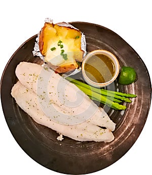 A Steamed basa fillet fish with asparagus and baked potato cheese, served with Thai green chili sauce in black round plate. photo