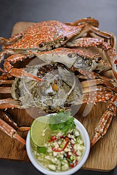 Steamed blue crab on wooden plate with spicy seafood sauce, Thai Food.