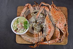 Steamed blue crab on wooden plate with spicy seafood sauce, Thai Food.