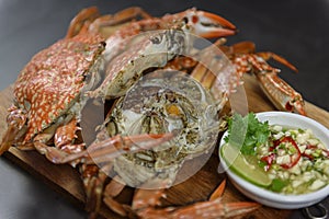 Steamed blue crab on wooden plate with spicy seafood sauce, Thai Food.