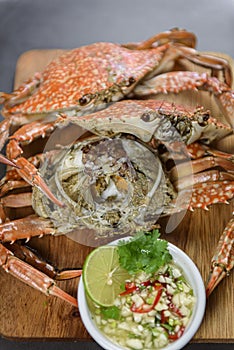 Steamed blue crab on wooden plate with spicy seafood sauce, Thai Food.