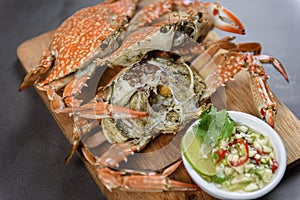 Steamed blue crab on wooden plate with spicy seafood sauce, Thai Food.