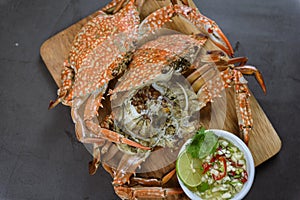 Steamed blue crab on wooden plate with spicy seafood sauce, Thai Food.