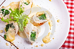 Steamed chicken cutlets stuffed with spinach on white plate. Top view