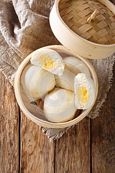 Steamed Chinese bun with custard cream stuff filling in bamboo wooden container. Vertical top view