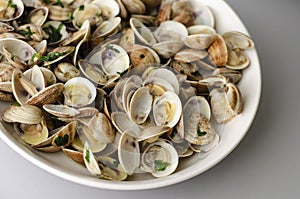 Steamed clams in garlic sauce in a white bowl.