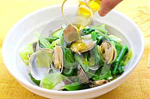Steamed clams with vegetables and oil in white bowl