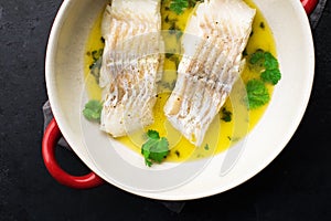 Steamed cod fillet butter-lemon sauce with herbs in the oven. Top view. In a baking dish. Healthy eating,