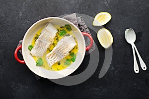 Steamed cod fillet butter-lemon sauce with herbs in the oven. Top view. In a baking dish. Healthy eating,