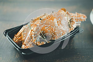 Steamed crab in black plastic container
