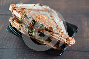 Steamed crab in black plastic container