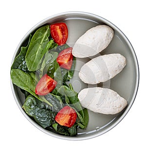 Steamed cutlets of three kinds of white meat with fresh spinach and tomatoes. Top view