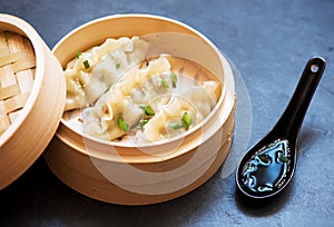 Steamed dumplings in bamboo steamer with soy sauce