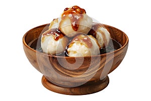 Steamed Faikakai dumplings topped with soy-based glaze, coconut syrup and sesame seeds in wooden bowl on white background