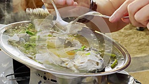 Steamed fish with lime pepper and various food ingredients on a table with Thai food dishes. Eating process