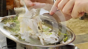 Steamed fish with lime pepper and various food ingredients on table with Thai food dishes. Eating process