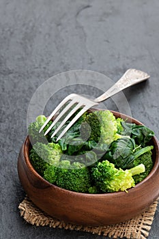Steamed fresh broccoli with spinach on black stone background