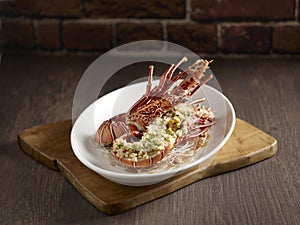 Steamed with Minced Garlic Bamboo Lobster served in a dish side view on wooden background