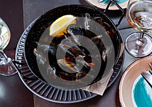Steamed mussels in shells with lemon in metal serving pan