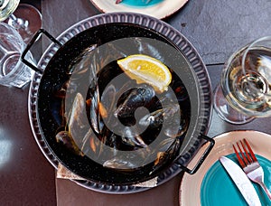 Steamed mussels in shells with lemon in metal serving pan