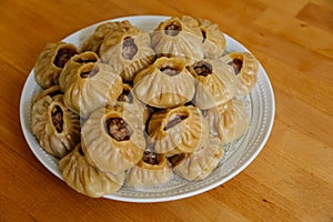 Steamed national Mongolian food dumpling Buuz filled with minced beef, white plate, wooden table, Close up east Siberian Buryats