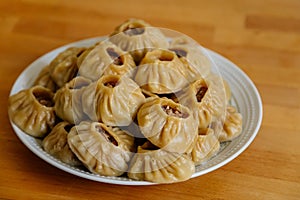 Steamed national Mongolian food dumpling Buuz filled with minced beef, white plate, wooden table, Close up east Siberian Buryats