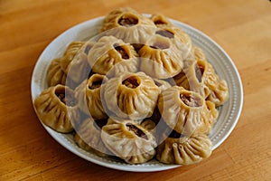 Steamed national Mongolian food dumpling Buuz filled with minced beef, white plate, wooden table, Close up east Siberian Buryats