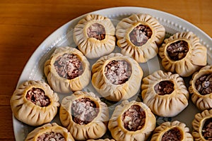 Steamed national Mongolian food dumpling Buuz filled with minced beef, white plate, wooden table, Close up east Siberian Buryats