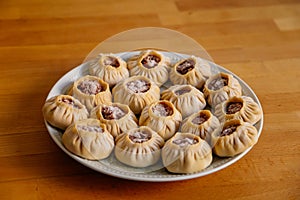 Steamed national Mongolian food dumpling Buuz filled with minced beef, white plate, wooden table, Close up east Siberian Buryats