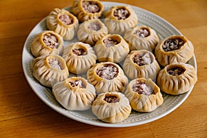 Steamed national Mongolian food dumpling Buuz filled with minced beef, white plate, wooden table, Close up east Siberian Buryats