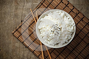 Steamed rice and black sesame seeds with chopsticks on a bamboo mat