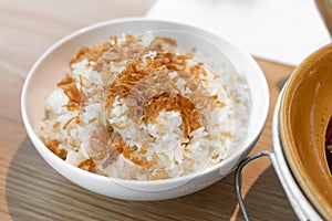 Steamed rice topped with fried shallots, serving on white bowl