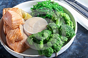 Steamed salmon with broccoli and seaweed salad. Diet healthy eating. On a dark background