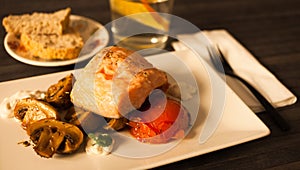 steamed salmon fillet on a pillow of fried mushrooms and tomatoes on a white plate