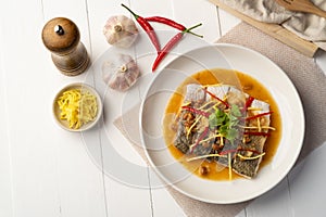 Steamed Seabass fish with Soybean Paste sauce in white plate.