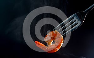 Steamed shrimp on fork isolated on dark background with copy space. Seafood buffet in restaurant concept. Use for seafood buffet p