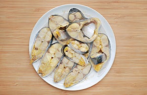 Steamed sliced striped catfish with on white plate against wooden board background