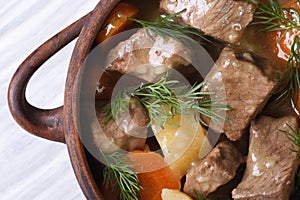 Steamed vegetables with meat and herbs in a pot macro.