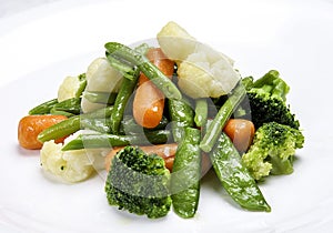 Steamed vegetables on white background. Cauliflower, peas, broccoli, carrots and asparagus beans