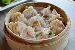 Steaming basket of Xiaolongbao, Chinese soup dumplings, in a traditional bamboo steamer